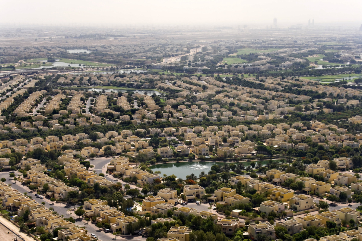 Suburban area with tan homes, landscaping, and a central lake.
