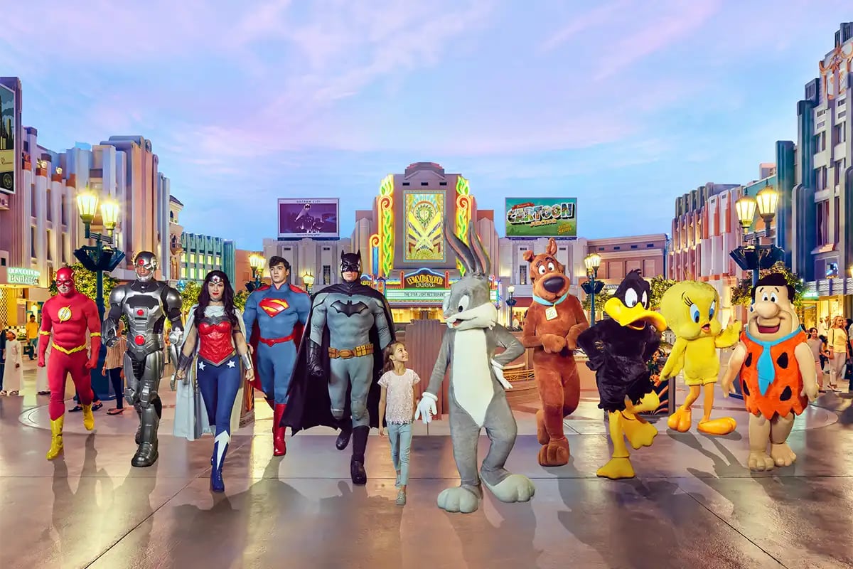Costumed characters and a girl walking past Warner Bros. and Cartoon Network buildings.