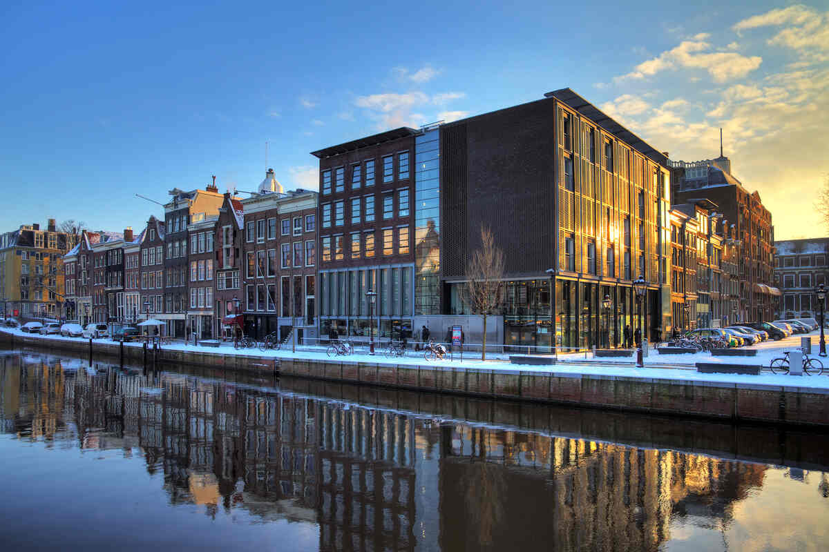 Modern building reflected in a winter canal at sunset.