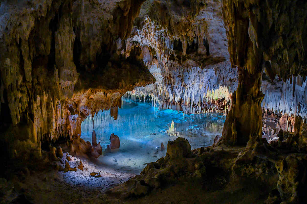 Subterranean pool in cavern adorned with stalactites and stalagmites.