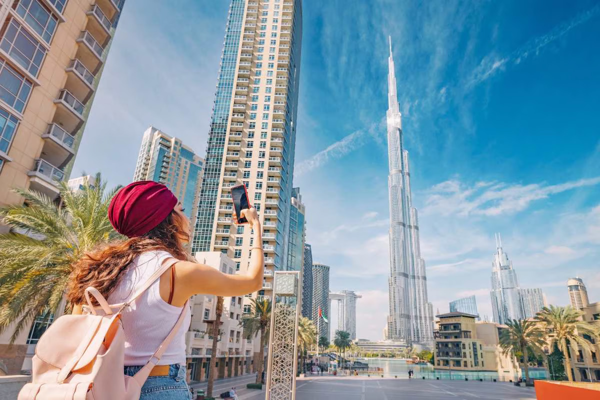 Woman photographing a skyscraper in a modern cityscape.