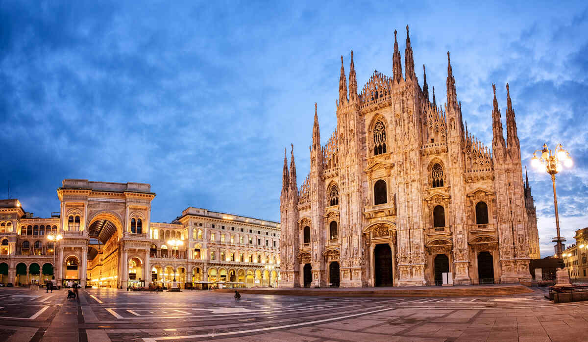 Gothic cathedral illuminated at dusk in a city square.
