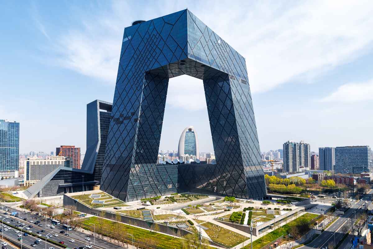 Large modern building with open structure amidst cityscape.