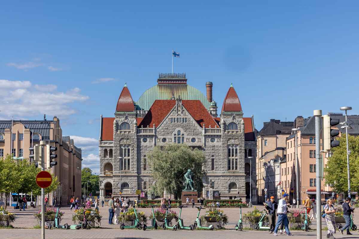 Stone building with electric scooters in front under clear sky.