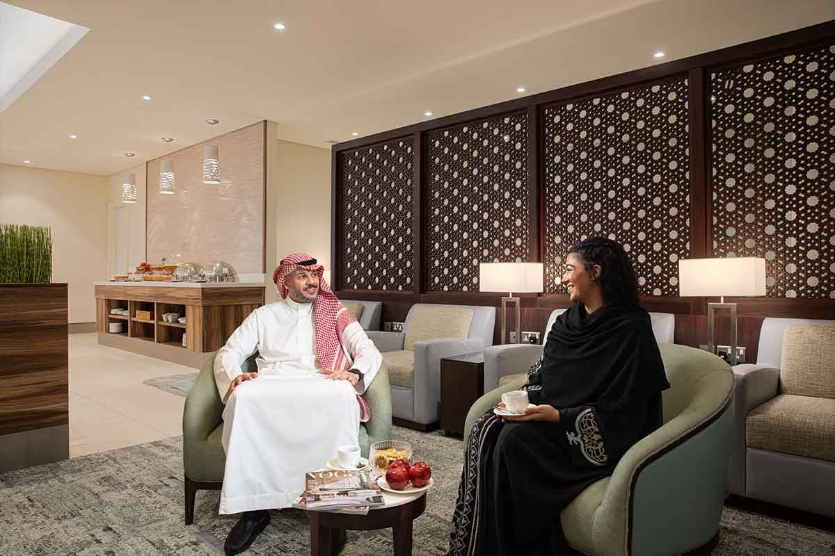 Man and woman in traditional attire relaxing in a modern lounge.