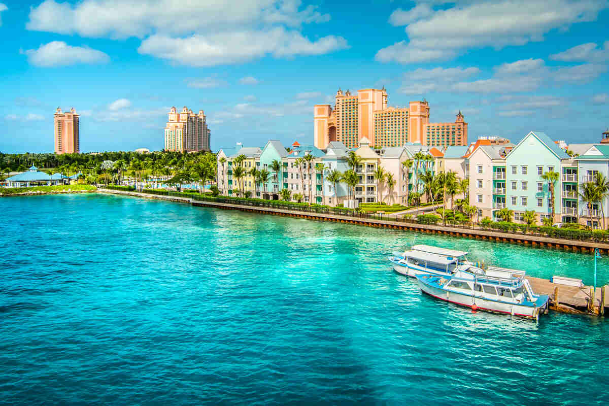 Two boats docked near pastel-colored buildings and turquoise waterway.