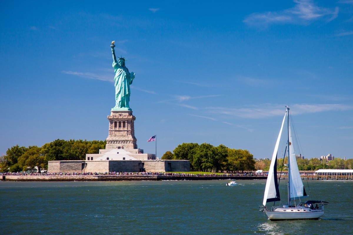 Sailboat near Statue of Liberty on island.