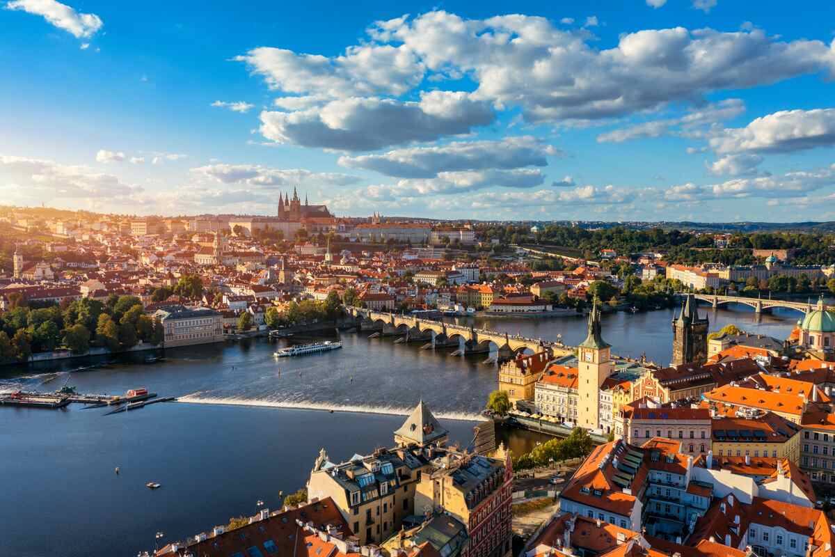City with buildings, a bridge, and a cathedral under a sunny sky.