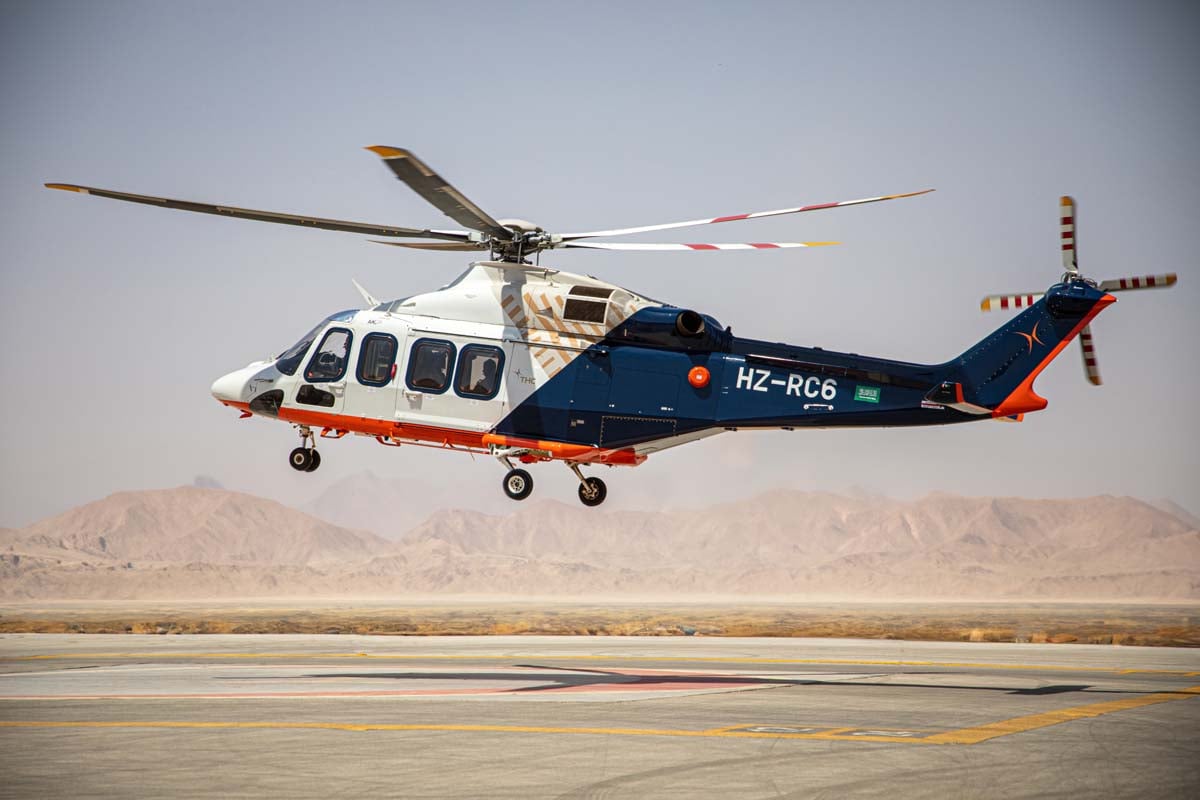 Helicopter landing at an airfield, with desert and mountains in the background.