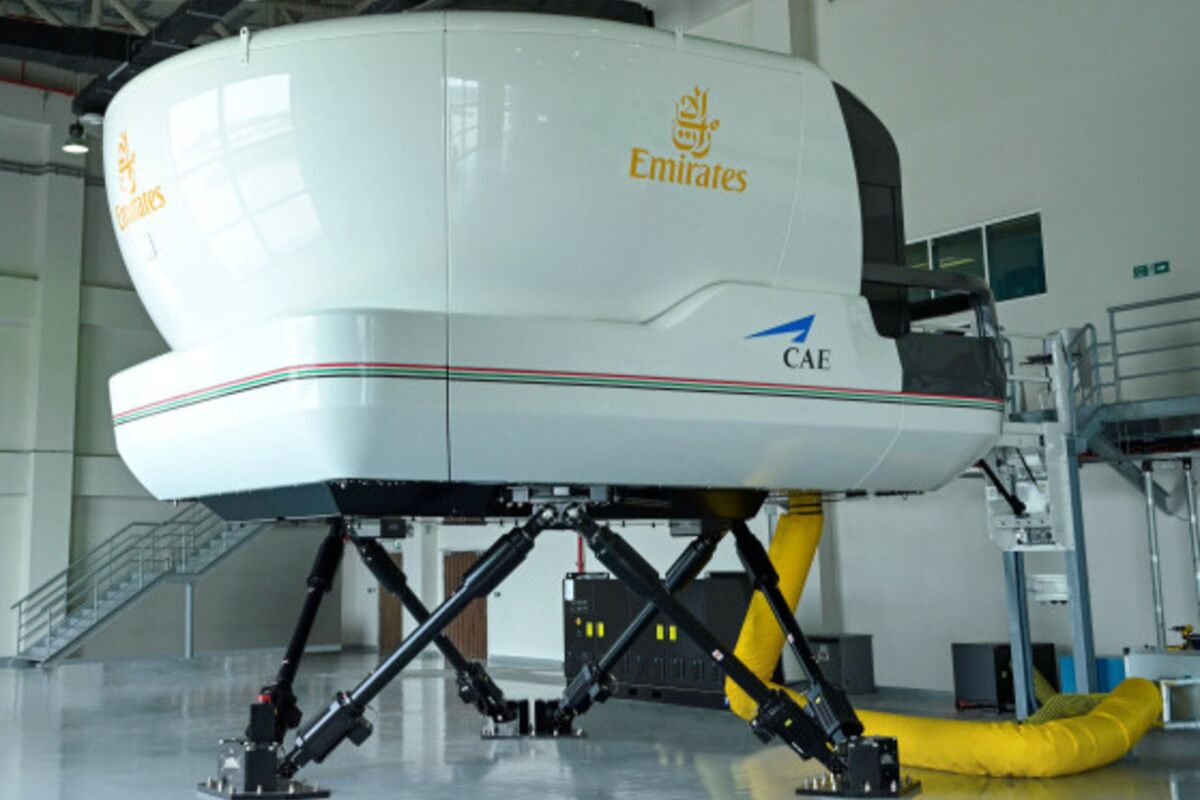 Emirates flight simulator on a motion platform in a hangar.