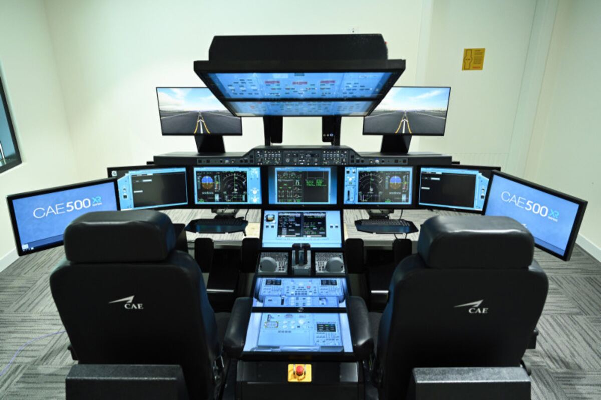 Flight simulator with multiple screens in a training room.