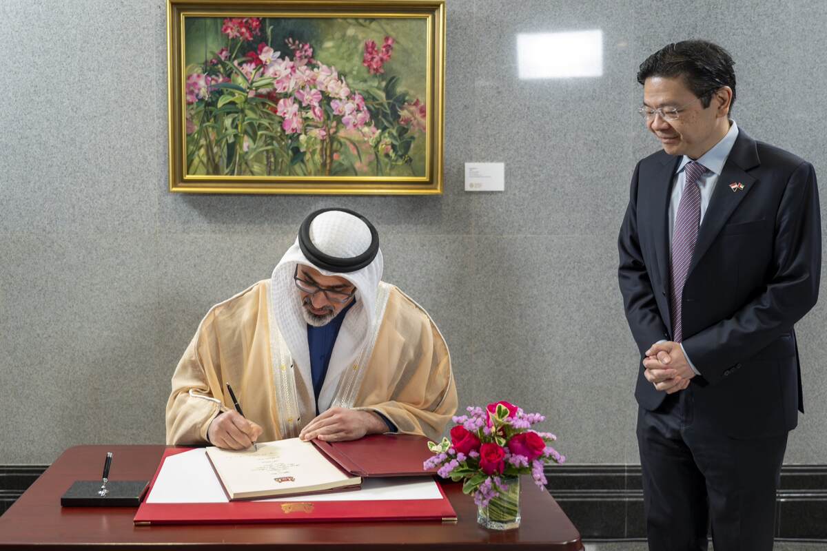 Sheikh Khaled writes a message in the guestbook at the Singapore Parliament House