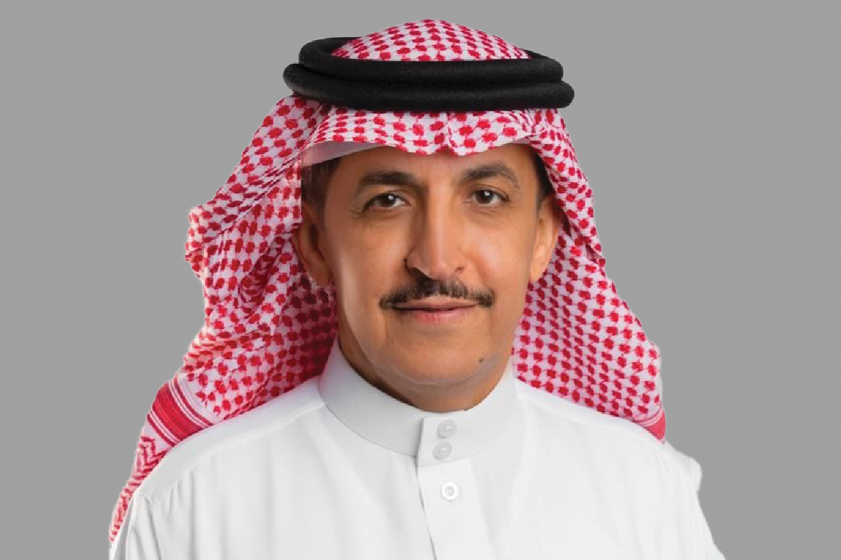 Man in traditional keffiyeh and thawb looks at camera.