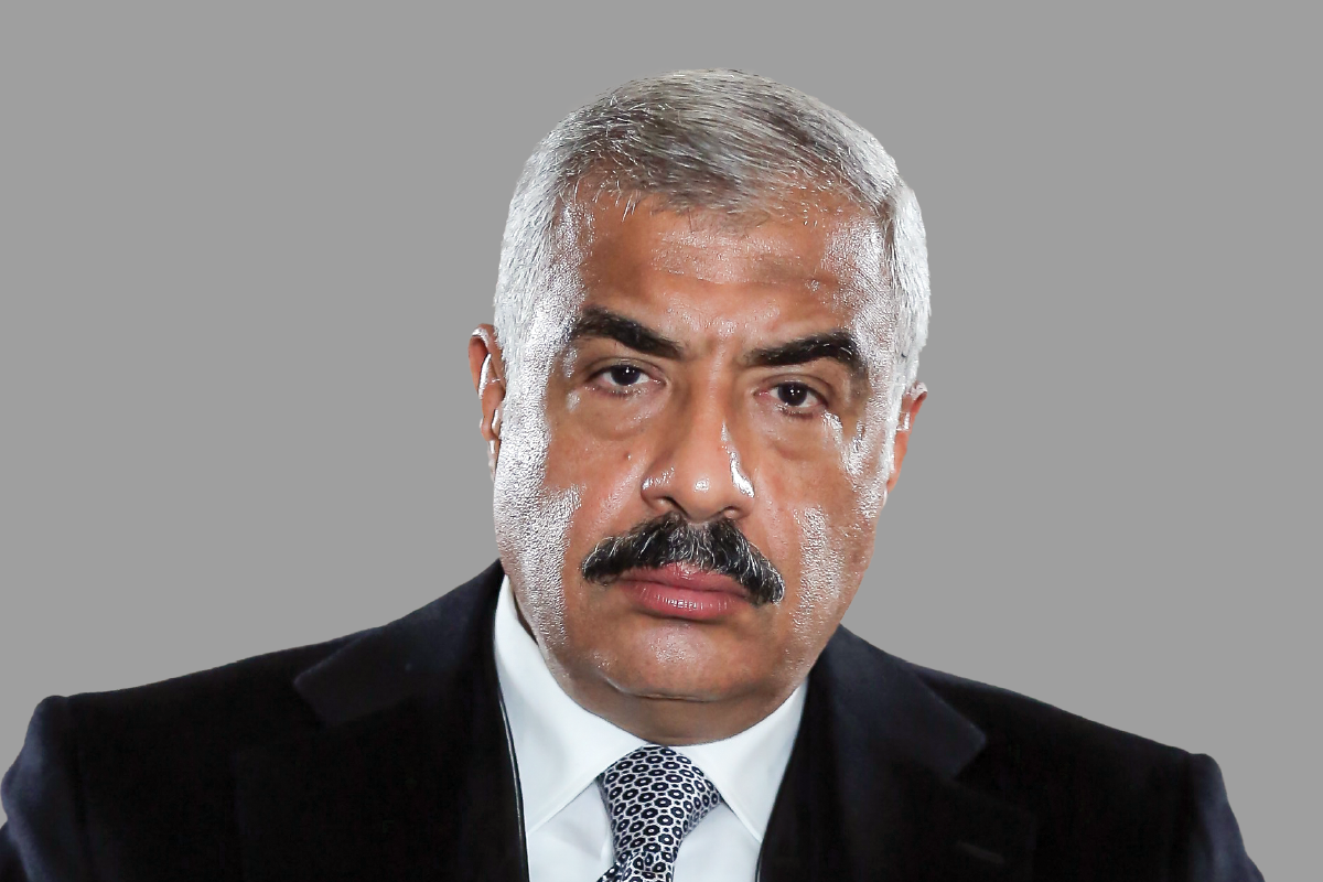 Man with graying hair and mustache in a dark suit and tie.