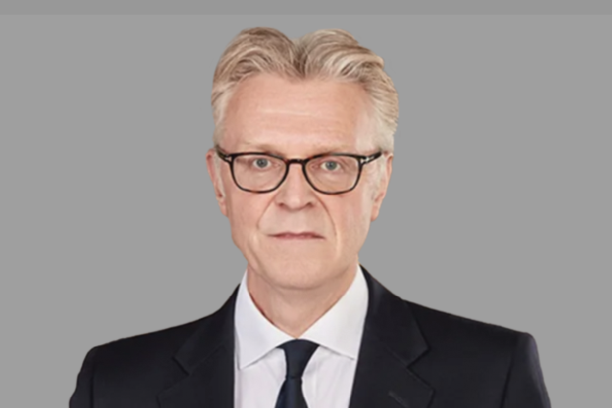 Man in glasses and dark suit, looking at the camera.